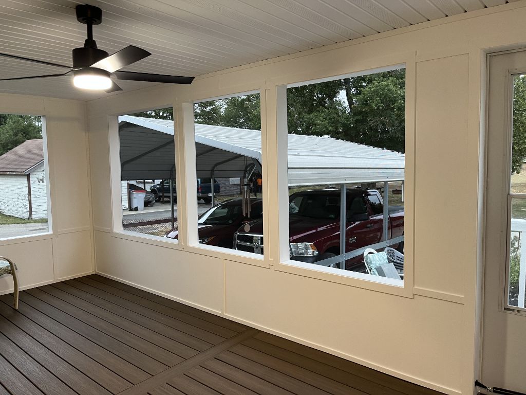 Screened porch with cream walls, ceiling fan, and composite decking