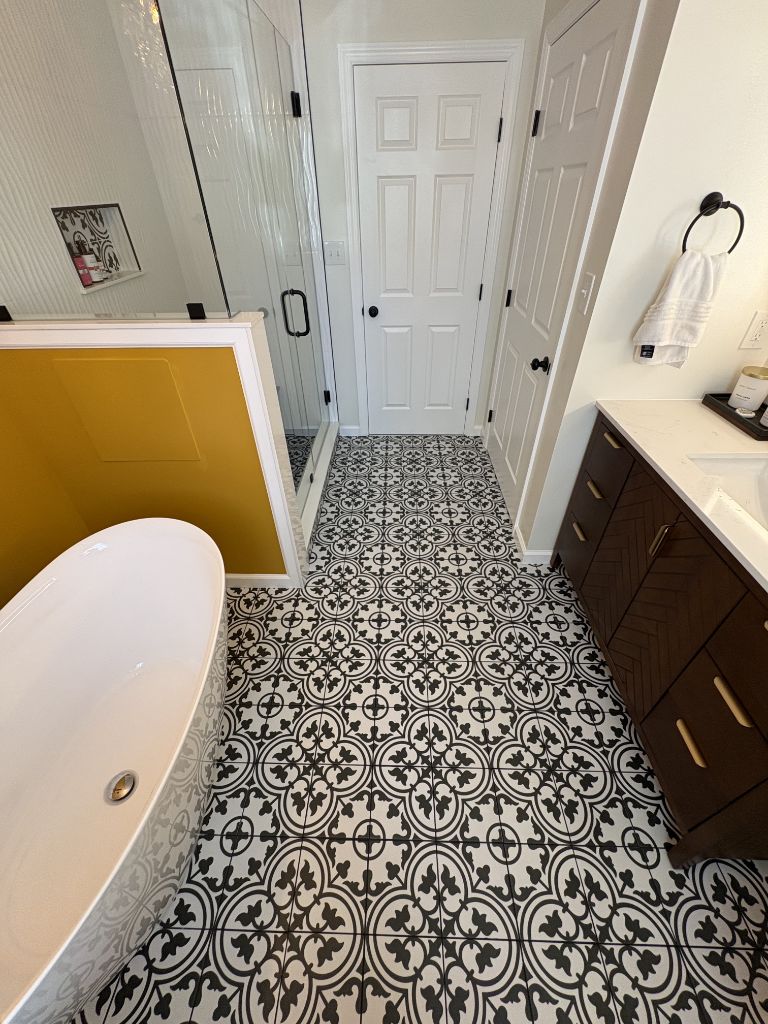 Bathroom with bold pattern tile floor, freestanding tub and glass shower