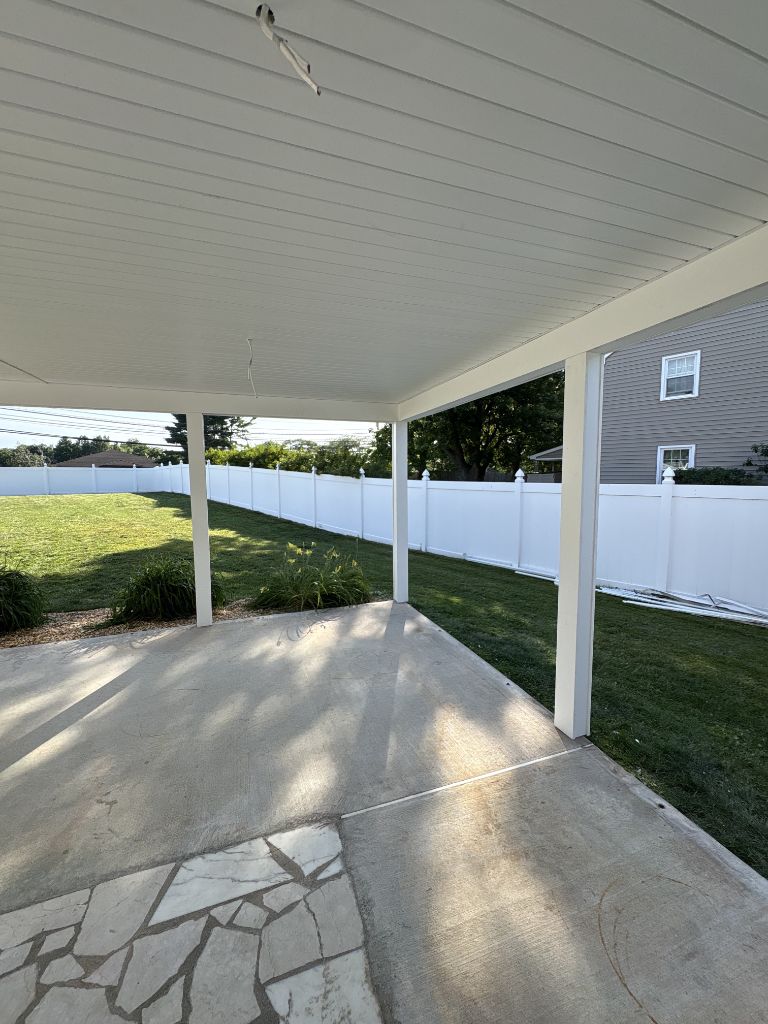White flat patio cover over concrete patio with vinyl fence