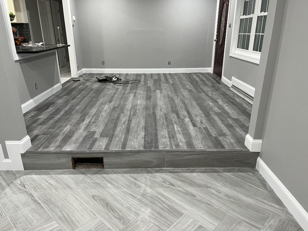 Gray LVP flooring installation with herringbone tile transition