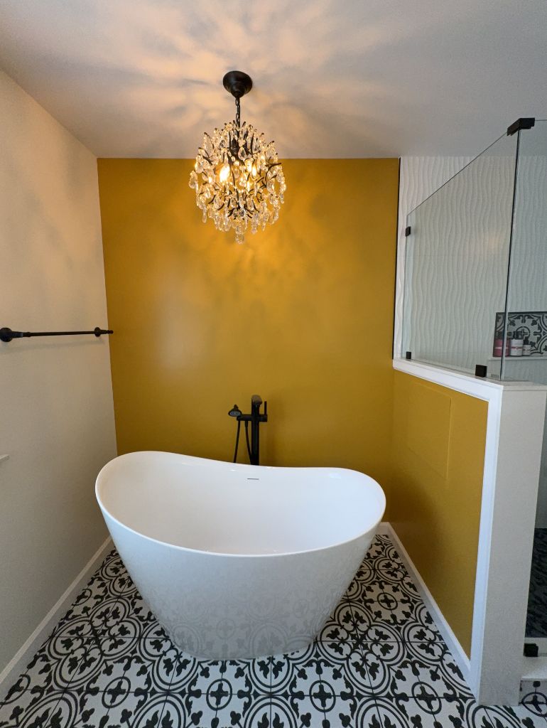Luxury bathroom with freestanding tub, crystal chandelier and yellow accent wall