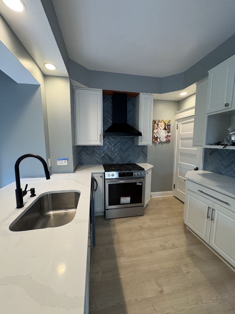 Full kitchen remodel with white cabinets, quartz counters and black fixtures