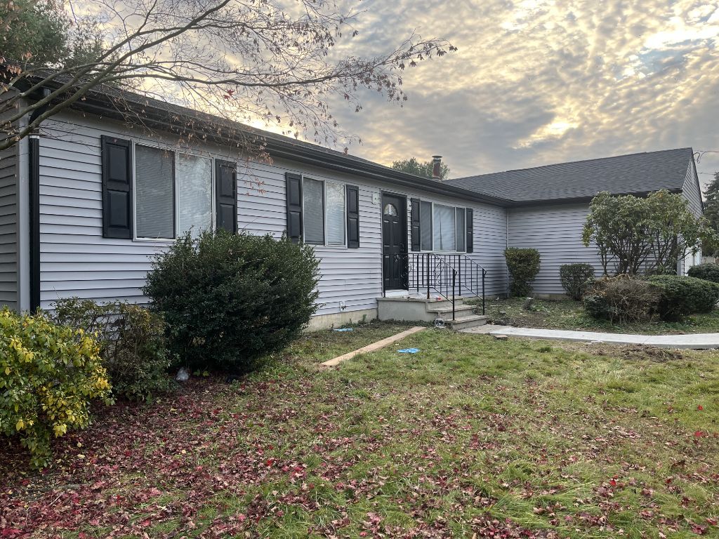 Light gray vinyl siding on single-story home with black shutters