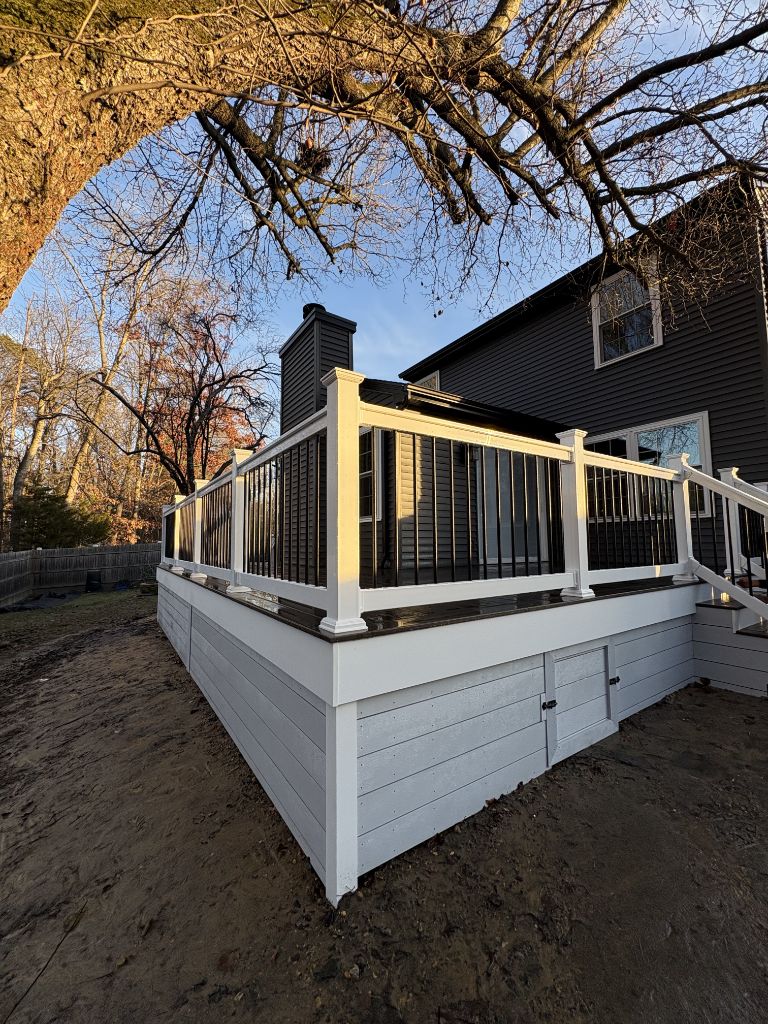 Freshly built deck with dark composite railing and white skirting