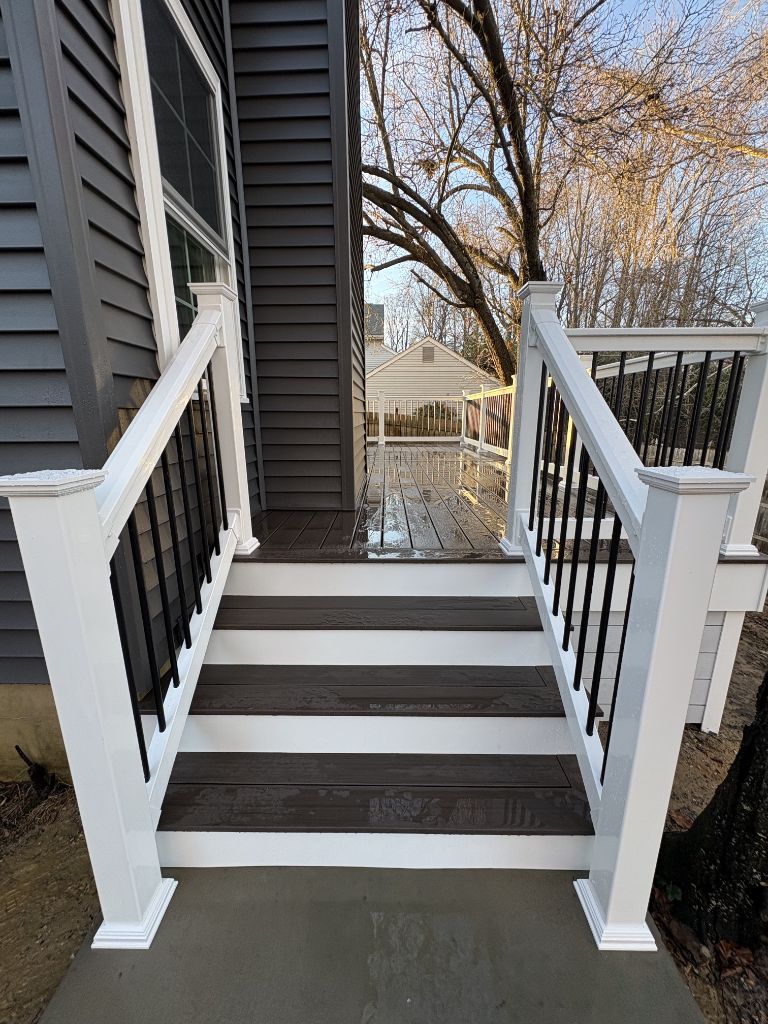 Completed dark composite deck with white railing and stairs