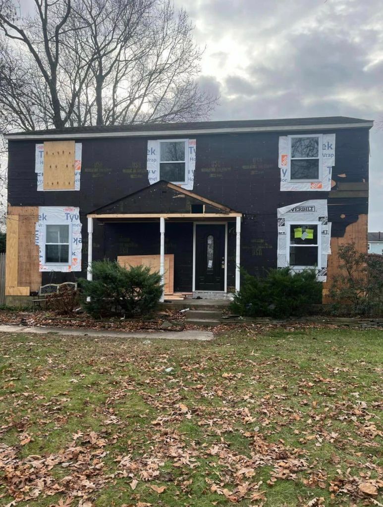 Siding installation in progress on colonial home